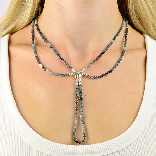 Necklace with blue beads worn by a person against a neutral background