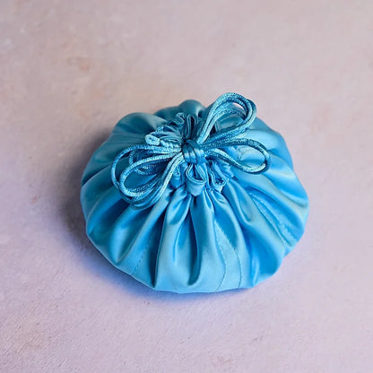 Blue satin drawstring pouch on a beige background