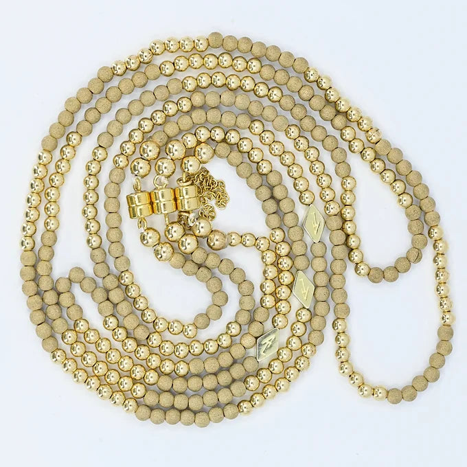 Gold beaded necklace on a white background