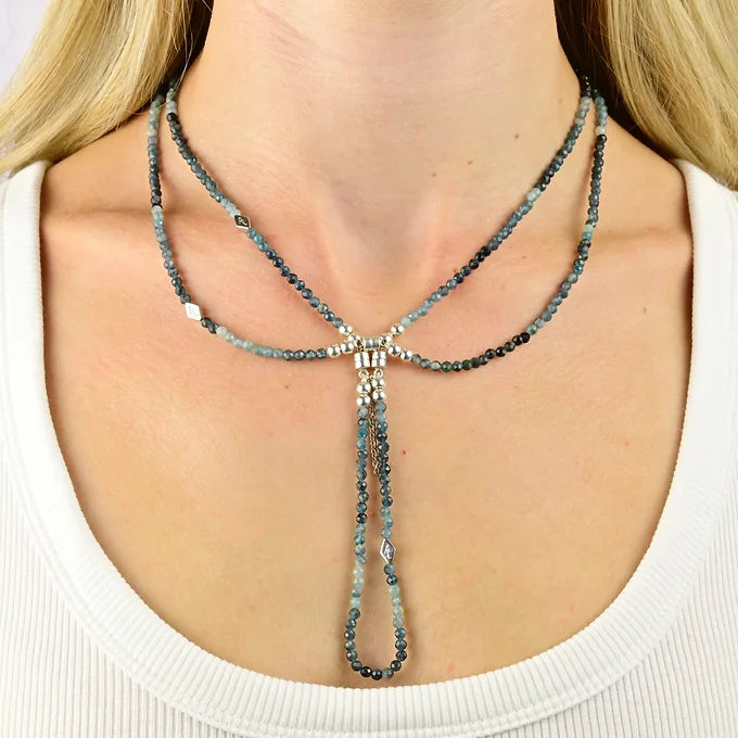 Necklace with blue beads worn by a person against a neutral background