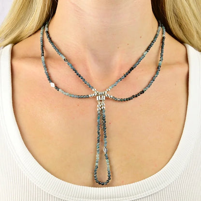 Necklace with blue beads worn by a person against a neutral background