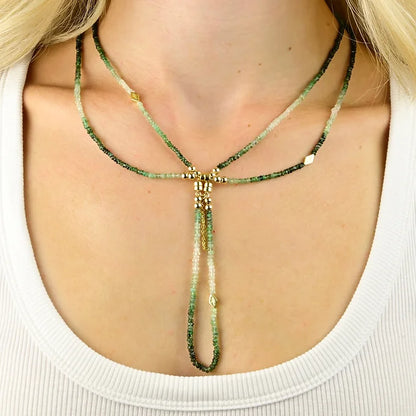 Green beaded necklace with gold accents worn by a person against a white background
