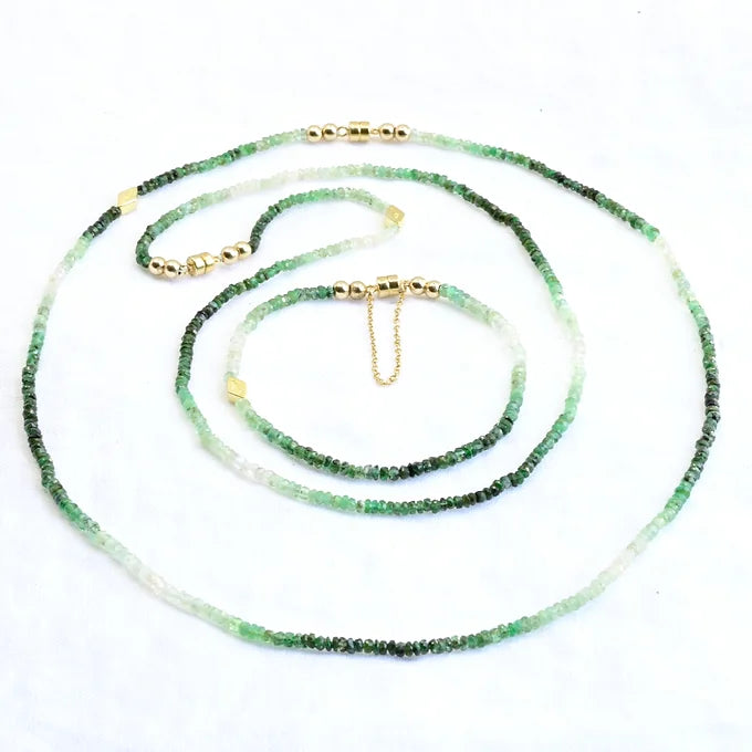 Green beaded necklace with gold accents on a white background