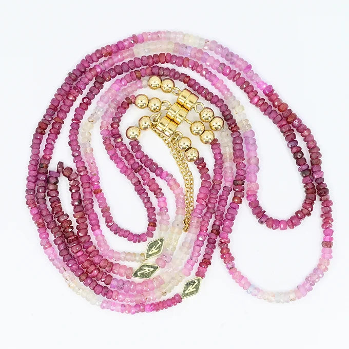 Set of pink beaded necklaces with gold and green accents on a white background