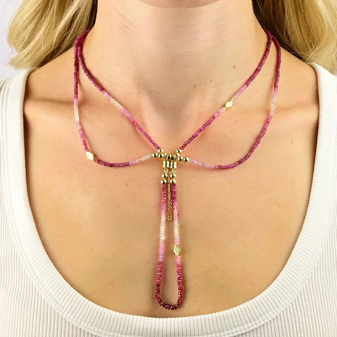 Necklace with pink and gold beads worn by a person on a white background