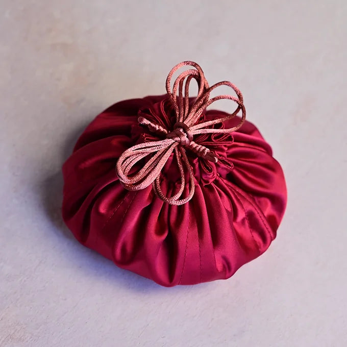 Red satin drawstring bag on a light gray background