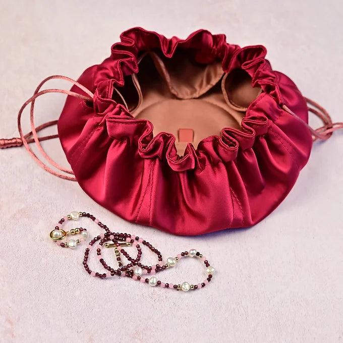 Red satin jewellery bag with a necklace 