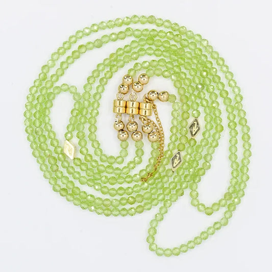 Green beaded necklace with gold accents on a white background