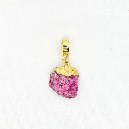 Gold pendant with a pink gemstone on a white background
