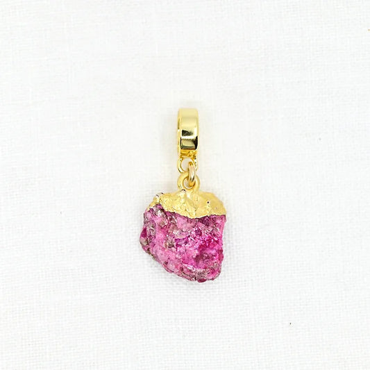 Gold pendant with a pink gemstone on a white background