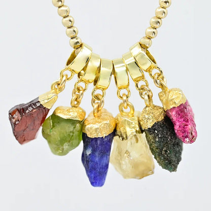Necklace with gold beads and colorful gemstone pendants on a white background