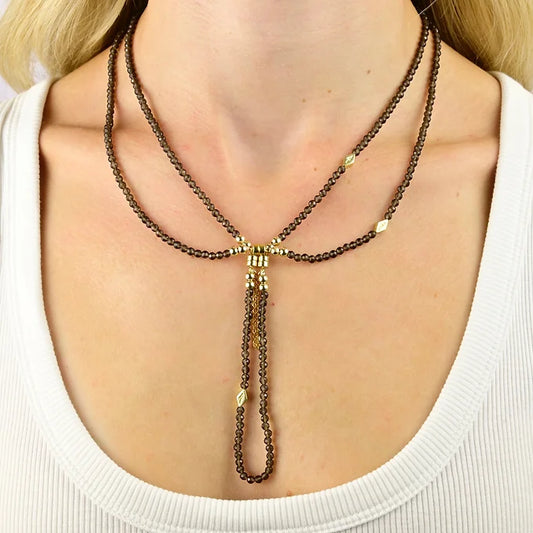 Necklace with gold and brown beads on a person wearing a white top