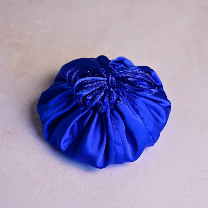 Blue satin drawstring bag on a beige background
