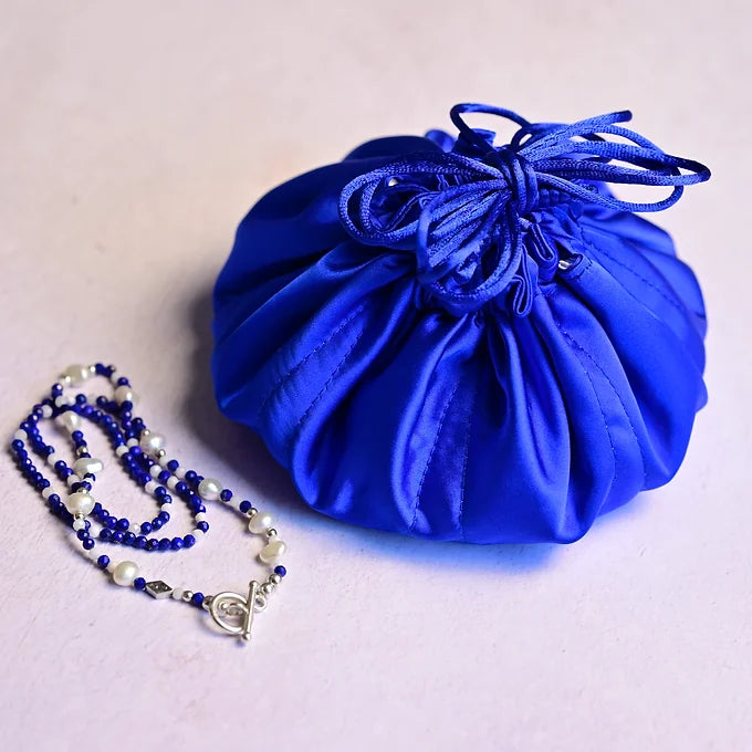 Blue drawstring bag with a necklace on a light background