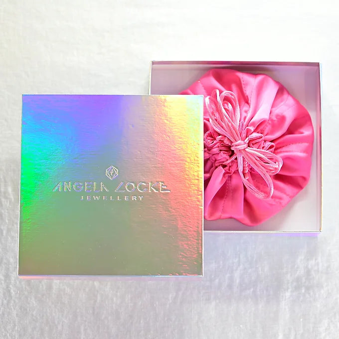 Jewellery box with a pink satin bag and 'Angela Locke Jewellery' branding on a textured white background.