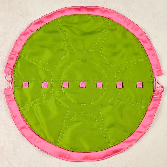 Round green mat with pink border and pink squares on a beige background