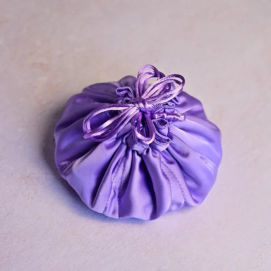 Purple satin drawstring bag with a ribbon on a light gray background