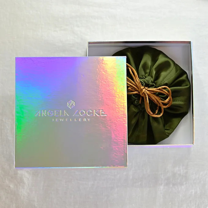 Jewellery box with a green satin bag and Angela Locke Jewellery card on a textured surface